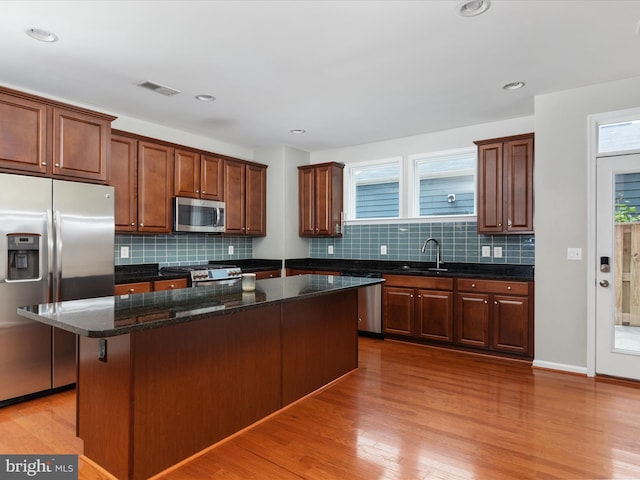 9411 Zebedee St, Manassas, VA 20110 - kitchen featuring appliances with stainless steel finishes, a sink, a center island, light wood finished floors, and decorative backsplash