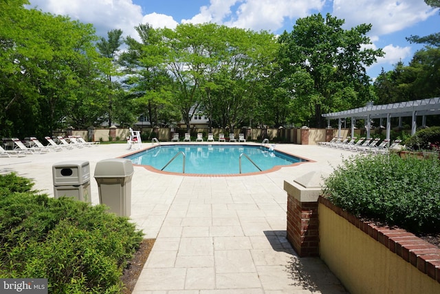 community pool featuring a patio area, fence, and view of scattered trees