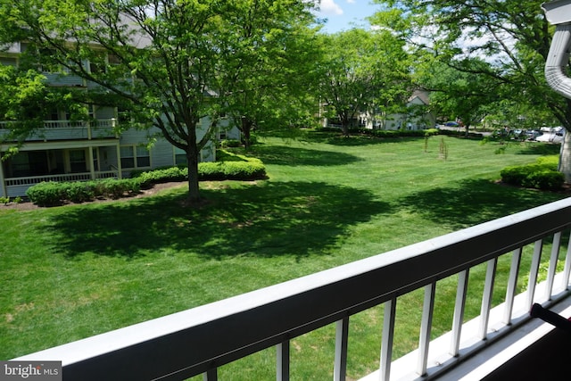 view of green lawn with a balcony