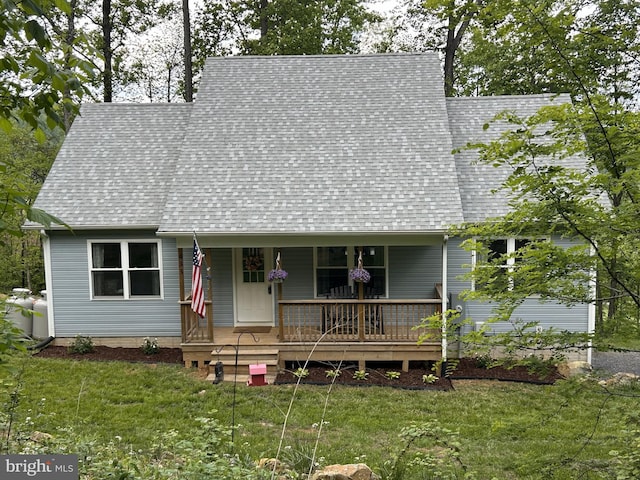 cape cod-style house with a shingled roof, a front yard, and covered porch