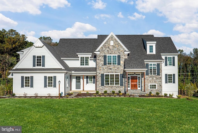 view of front of house featuring stone siding, a front yard, and a shingled roof