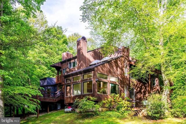 rear view of property with a chimney, a sunroom, and a deck