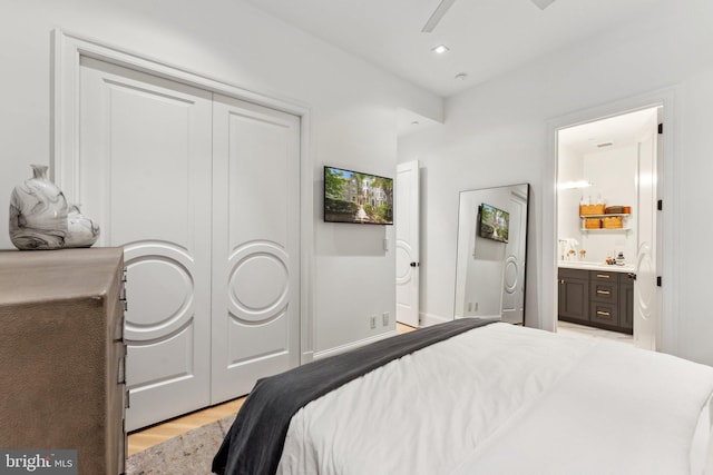 bedroom featuring light wood finished floors, a closet, and ensuite bathroom