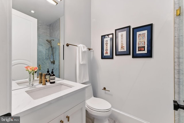 bathroom with a stall shower, toilet, vanity, and baseboards