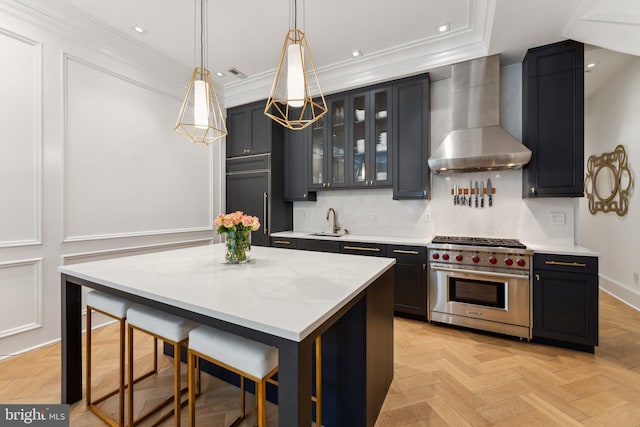 kitchen with designer stove, wall chimney range hood, a sink, ornamental molding, and backsplash