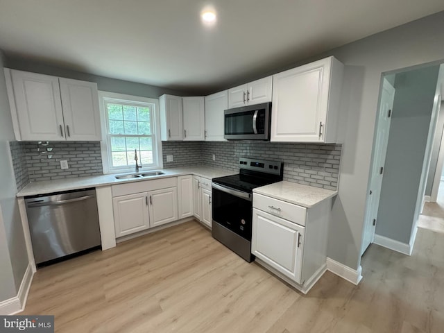 581 Milford Neck Rd, Milford, DE 19963 - kitchen featuring appliances with stainless steel finishes, a sink, light wood-style flooring, light countertops, and white cabinetry