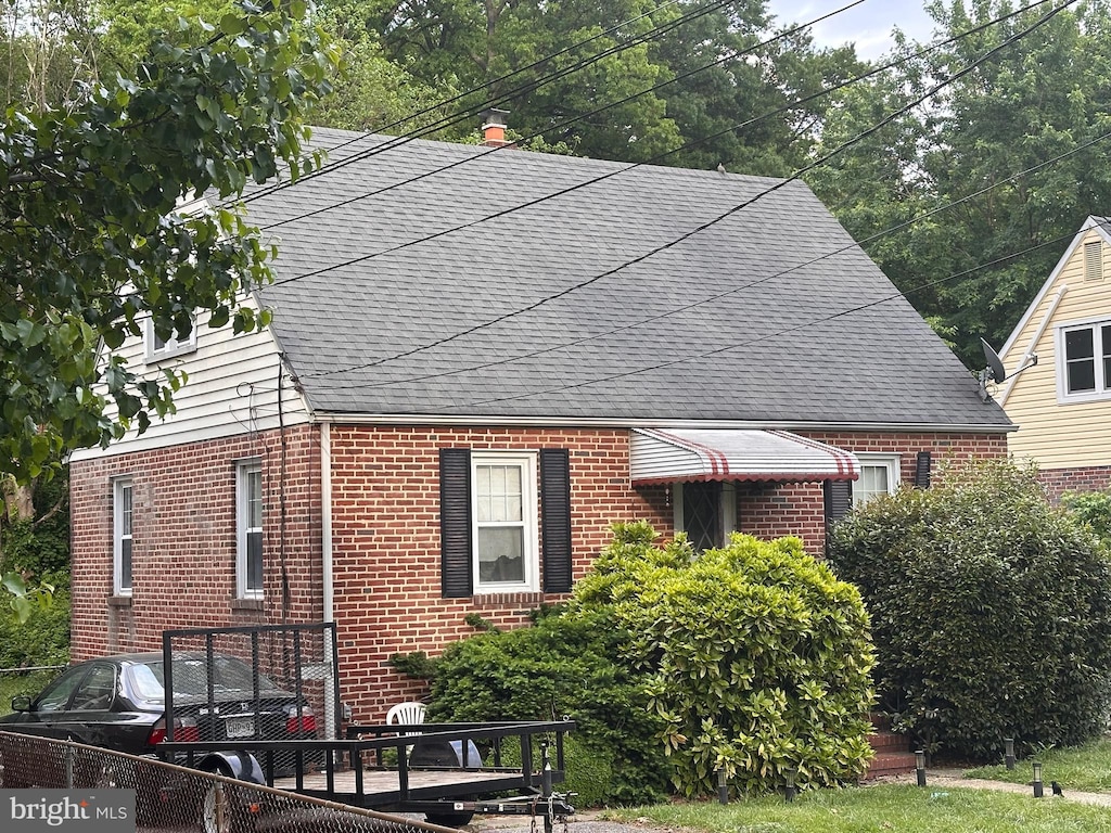 view of side of property with brick siding and roof with shingles