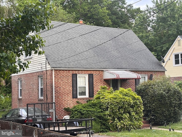 view of side of property with brick siding and roof with shingles