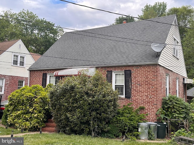 view of home's exterior with brick siding and a shingled roof
