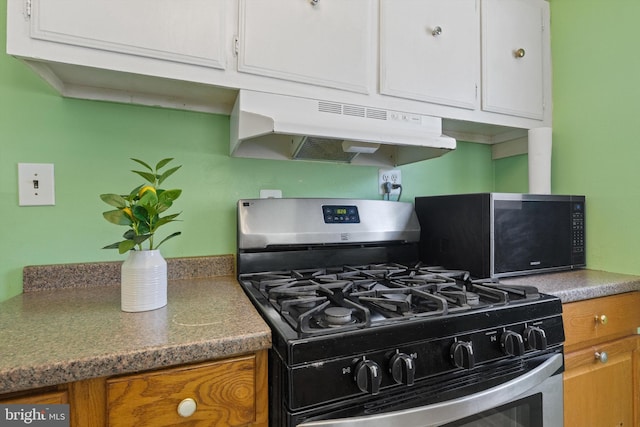 4205 73rd Ave, Hyattsville, MD 20784 - kitchen with stainless steel gas range, under cabinet range hood, brown cabinets, white cabinetry, and black microwave