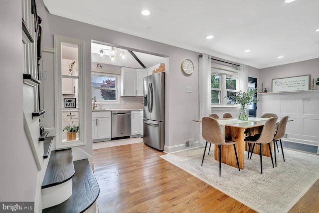 dining area with ornamental molding, light wood-type flooring, recessed lighting, baseboards, and a chandelier