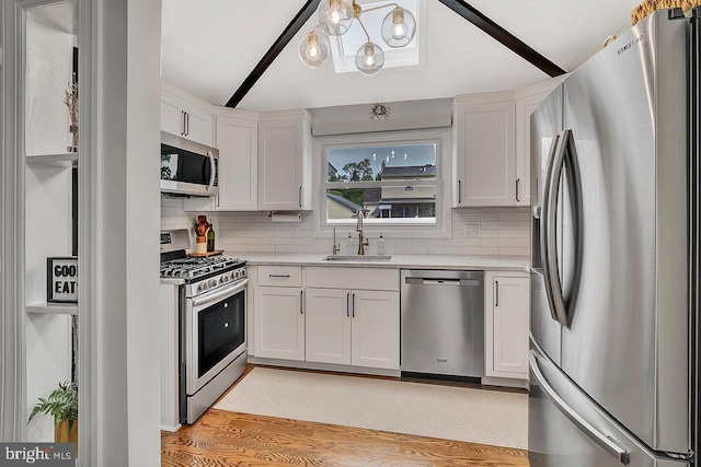 kitchen with appliances with stainless steel finishes, a sink, decorative backsplash, and white cabinets