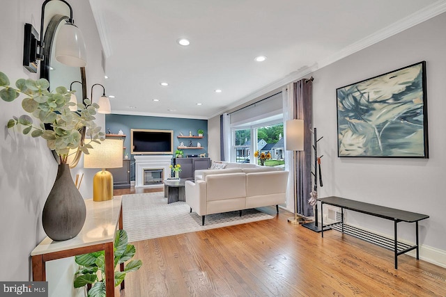 living room featuring crown molding, recessed lighting, wood finished floors, and a glass covered fireplace