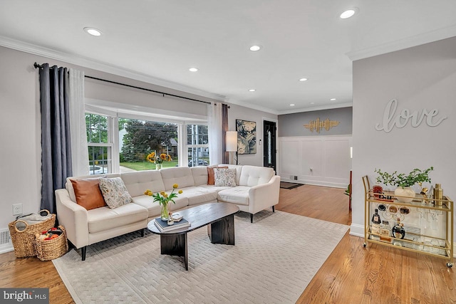 living area featuring ornamental molding, wood finished floors, recessed lighting, wainscoting, and a decorative wall
