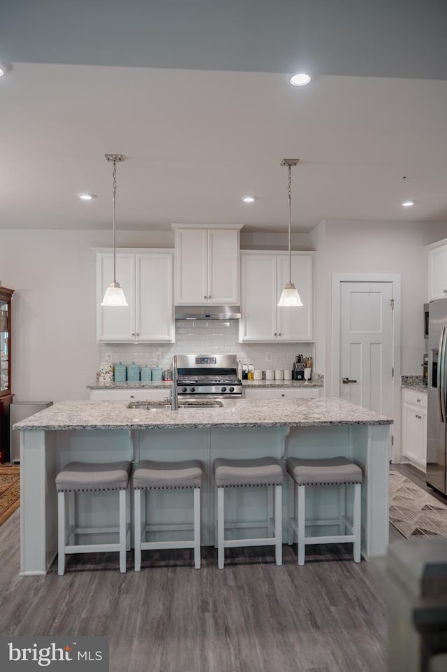 8212 Hickory Hollow Dr, Glen Burnie, MD 21060 - kitchen with under cabinet range hood, stainless steel appliances, decorative backsplash, white cabinets, and recessed lighting