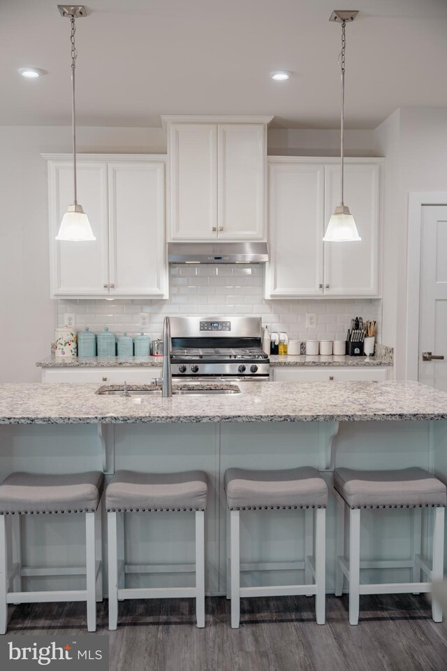 8212 Hickory Hollow Dr, Glen Burnie, MD 21060 - kitchen with stainless steel gas stove, under cabinet range hood, white cabinets, backsplash, and light stone countertops