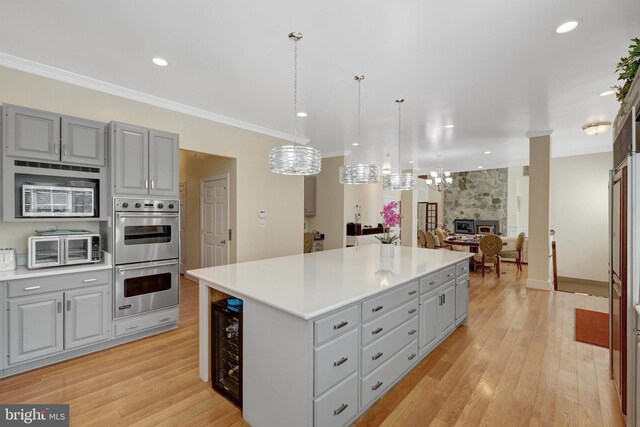 kitchen featuring gray cabinetry, double oven, a chandelier, a kitchen island, and light wood-style flooring