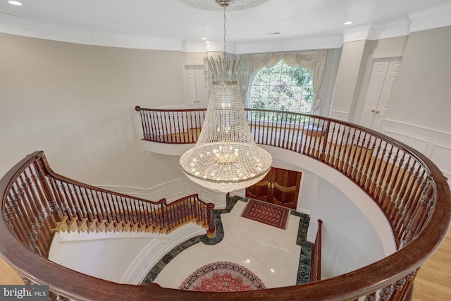 stairway with a chandelier, ornamental molding, recessed lighting, and a decorative wall