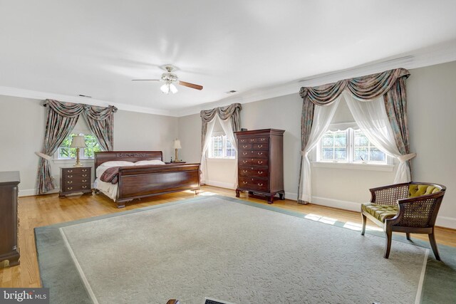 bedroom featuring light wood-style flooring, ornamental molding, baseboards, and ceiling fan