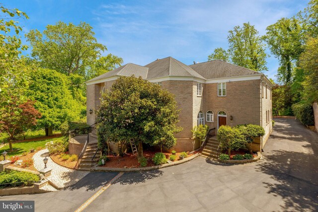 view of property exterior featuring brick siding and stairs