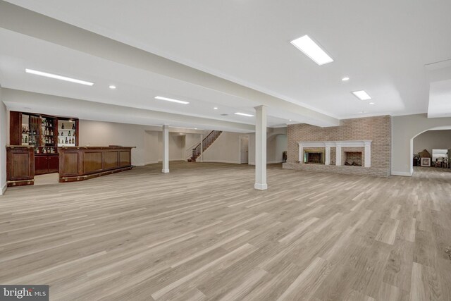 finished below grade area featuring a bar, stairs, light wood-type flooring, baseboards, and recessed lighting