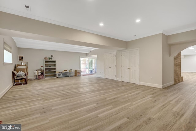 below grade area with arched walkways, ornamental molding, light wood finished floors, baseboards, and recessed lighting