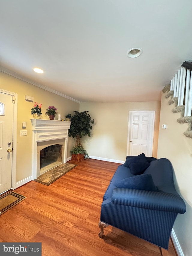 707 Mentor Ave, Capitol Heights, MD 20743 - living room featuring baseboards, a fireplace with raised hearth, ornamental molding, stairs, and wood finished floors