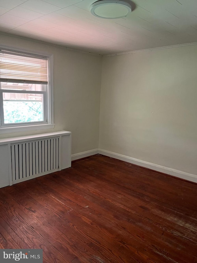437 52nd St, Baltimore, MD 21224 - spare room featuring radiator, dark wood-type flooring, baseboards, and crown molding