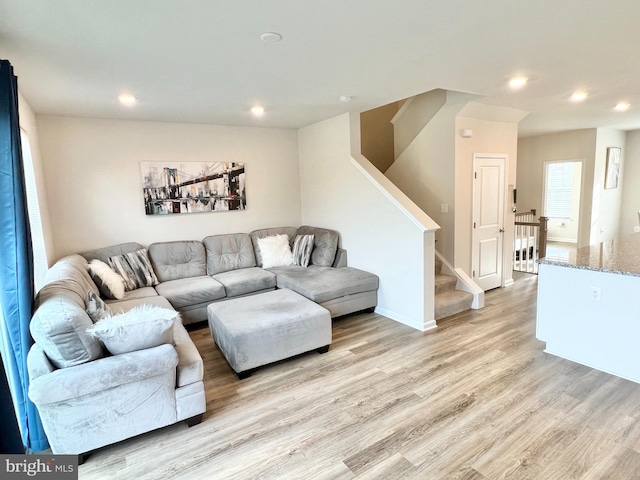living room featuring light wood-type flooring, recessed lighting, and stairway