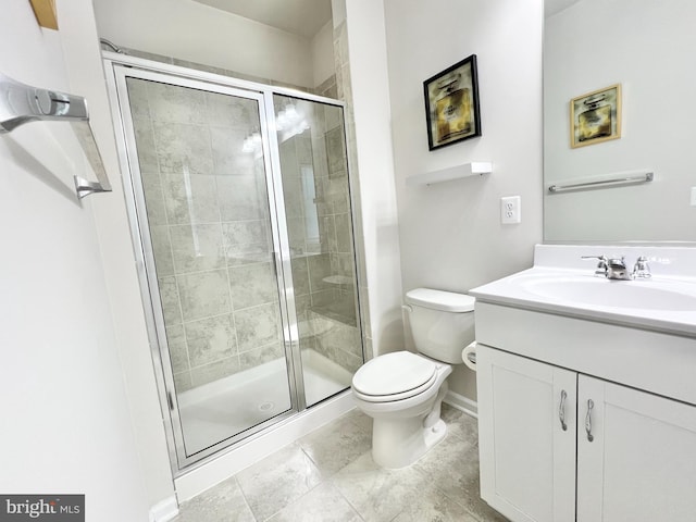 bathroom with a shower stall, toilet, vanity, and baseboards