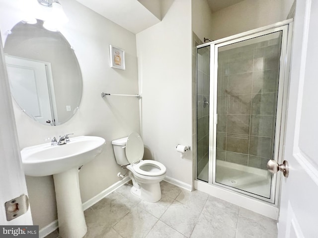 bathroom with a shower stall, baseboards, toilet, tile patterned floors, and a sink