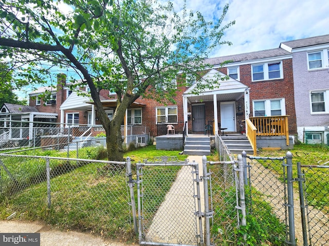 1351 Cambria St, Baltimore, MD 21225 - view of property featuring a gate, brick siding, a fenced front yard, and a porch