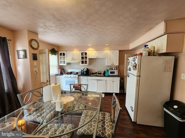 1351 Cambria St, Baltimore, MD 21225 - kitchen with white appliances, dark wood finished floors, a textured ceiling, dark countertops, and glass insert cabinets