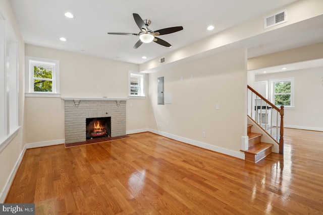 1706 Otis St NE, Washington, DC 20018 - unfurnished living room featuring light wood finished floors, healthy amount of natural light, a brick fireplace, stairway, and recessed lighting