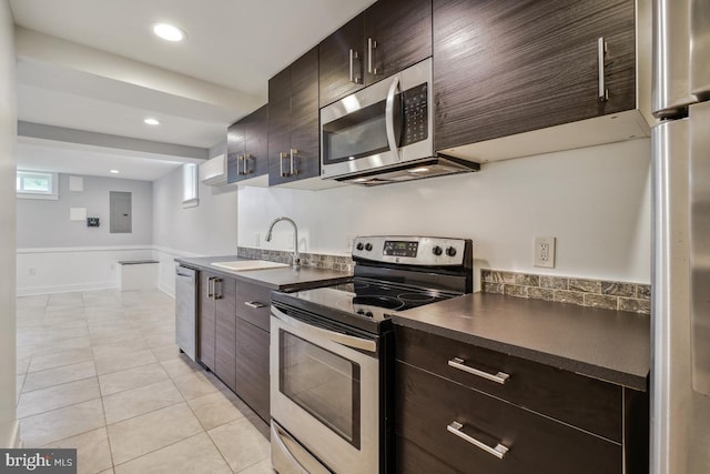 1706 Otis St NE, Washington, DC 20018 - kitchen with appliances with stainless steel finishes, dark countertops, a sink, light tile patterned floors, and dark brown cabinets