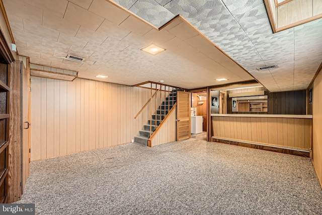 finished below grade area with wooden walls, stairway, and washer / dryer