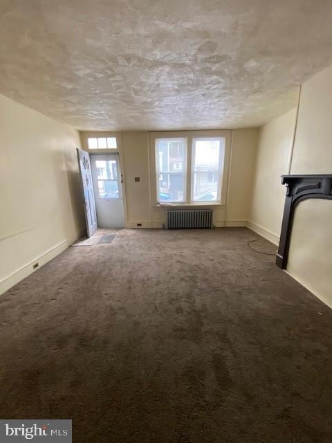 511 W Arch St, Pottsville, PA 17901 - unfurnished living room with radiator heating unit, a textured ceiling, carpet floors, and baseboards