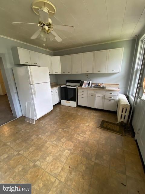 511 W Arch St, Pottsville, PA 17901 - kitchen with electric stove, freestanding refrigerator, white cabinets, radiator heating unit, and a sink