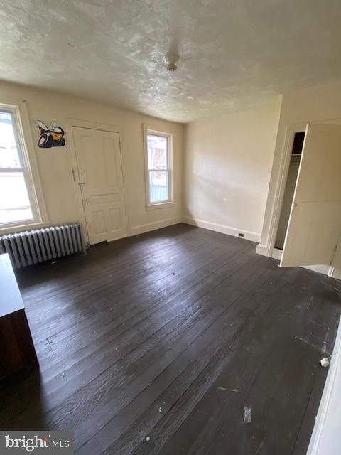 511 W Arch St, Pottsville, PA 17901 - unfurnished living room featuring radiator, dark wood finished floors, and baseboards