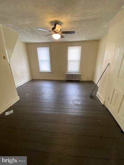 511 W Arch St, Pottsville, PA 17901 - spare room featuring radiator heating unit, baseboards, dark wood finished floors, and a ceiling fan