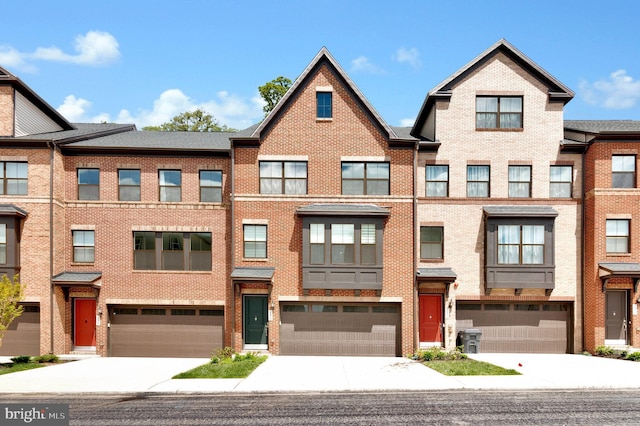 multi unit property with driveway, a garage, and brick siding