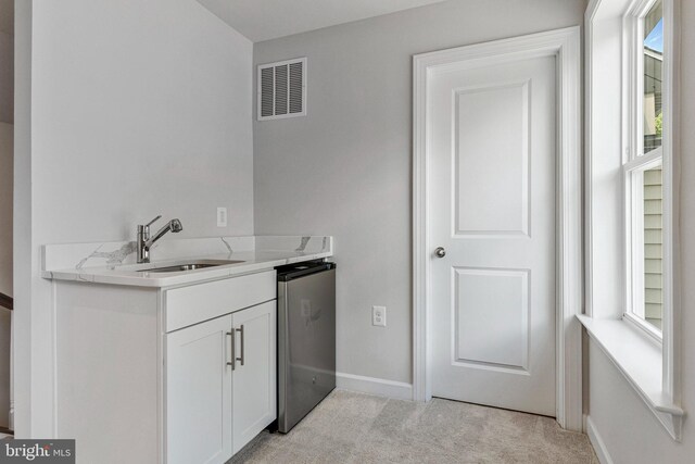 kitchen featuring light colored carpet, a sink, white cabinetry, baseboards, and light countertops
