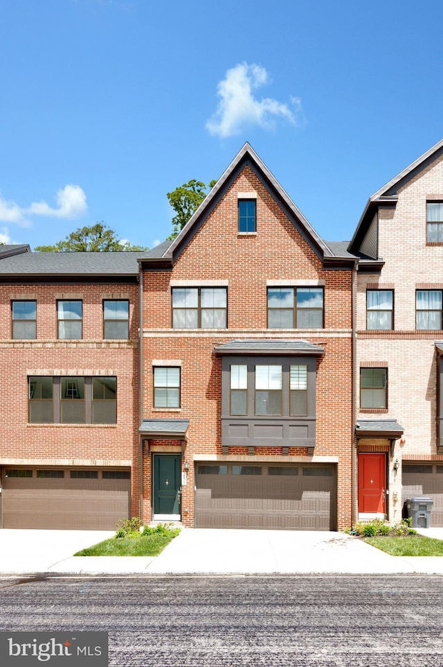 multi unit property with driveway, an attached garage, and brick siding