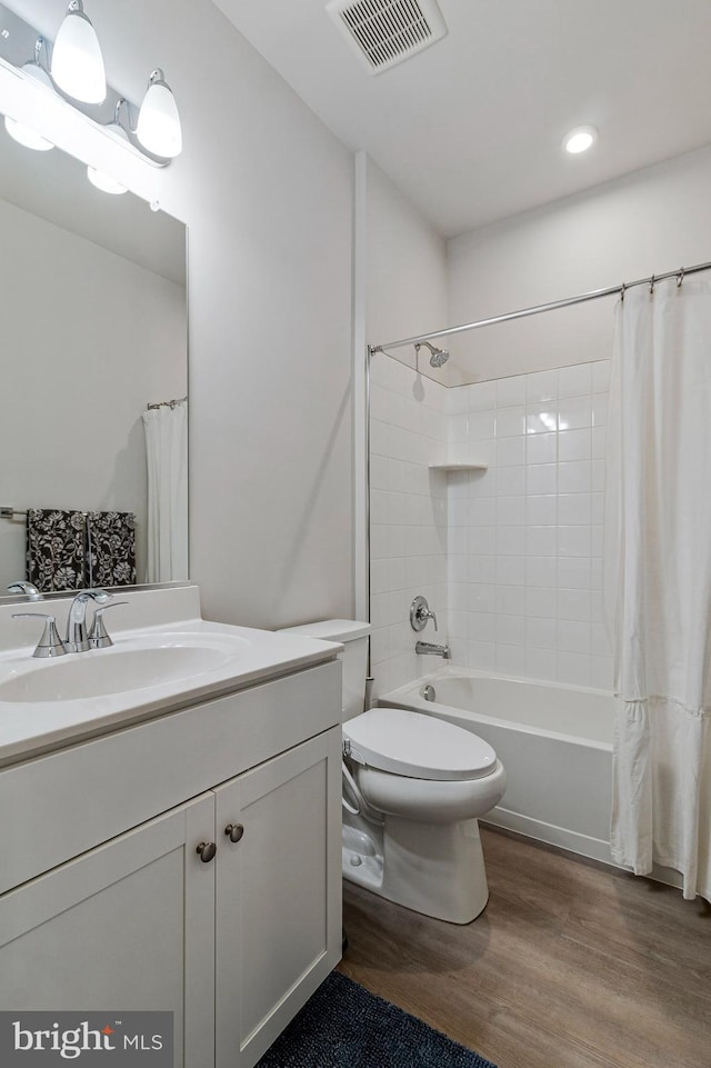 bathroom with wood finished floors, vanity, toilet, shower / tub combo, and recessed lighting
