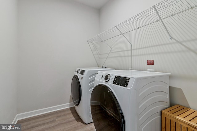 laundry room featuring washing machine and dryer, baseboards, and light wood-style floors