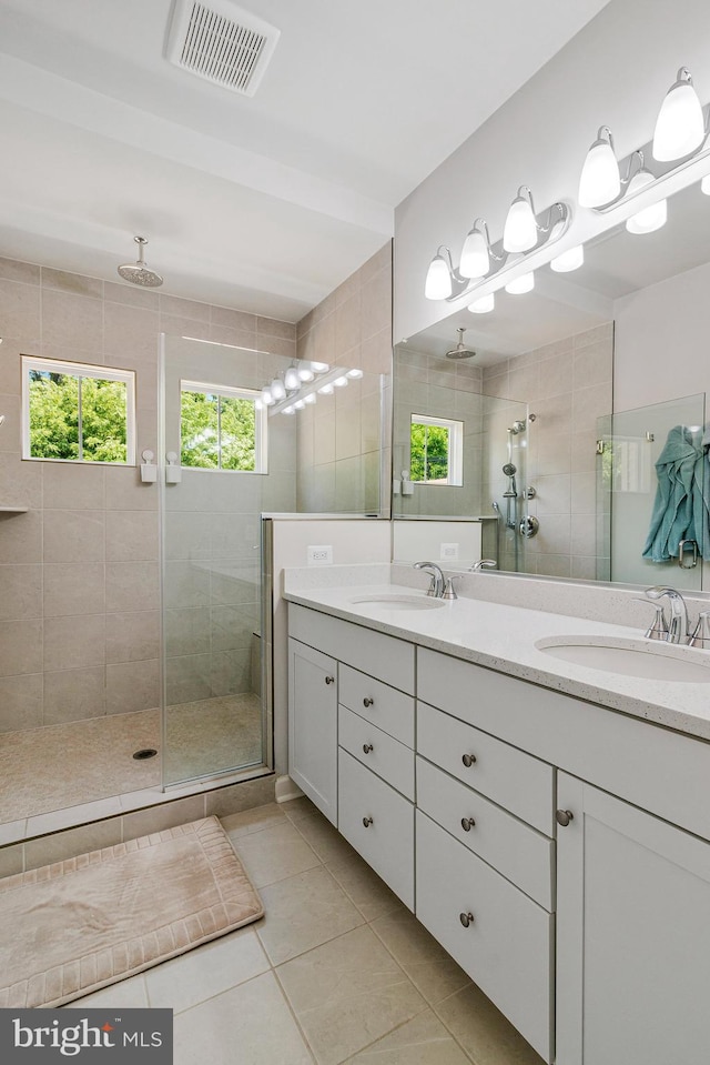 bathroom featuring tile patterned flooring, a stall shower, and double vanity