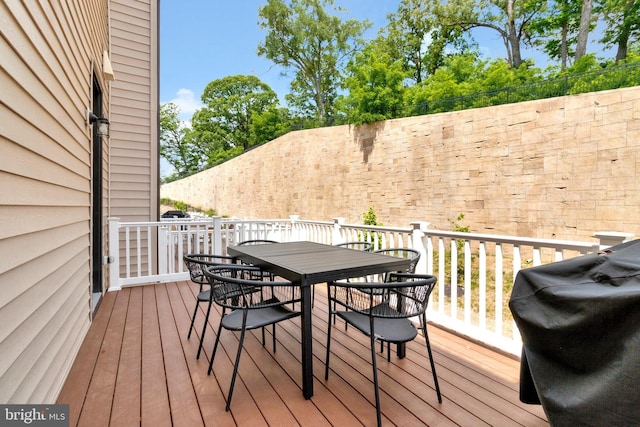 wooden terrace featuring a grill and outdoor dining space