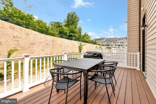 deck with outdoor dining space, area for grilling, and fence