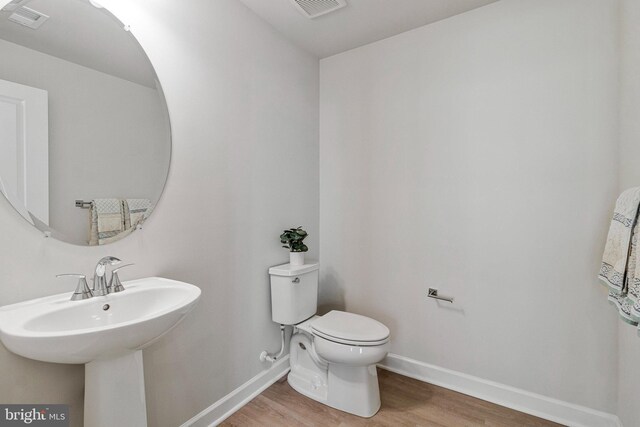 bathroom with wood finished floors, baseboards, toilet, and a sink
