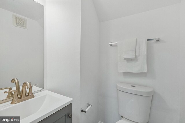 bathroom with toilet, vanity, and vaulted ceiling